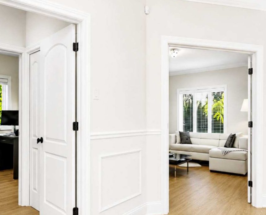 Primed white doors, casing, baseboard and wall panel moulding in a hallway